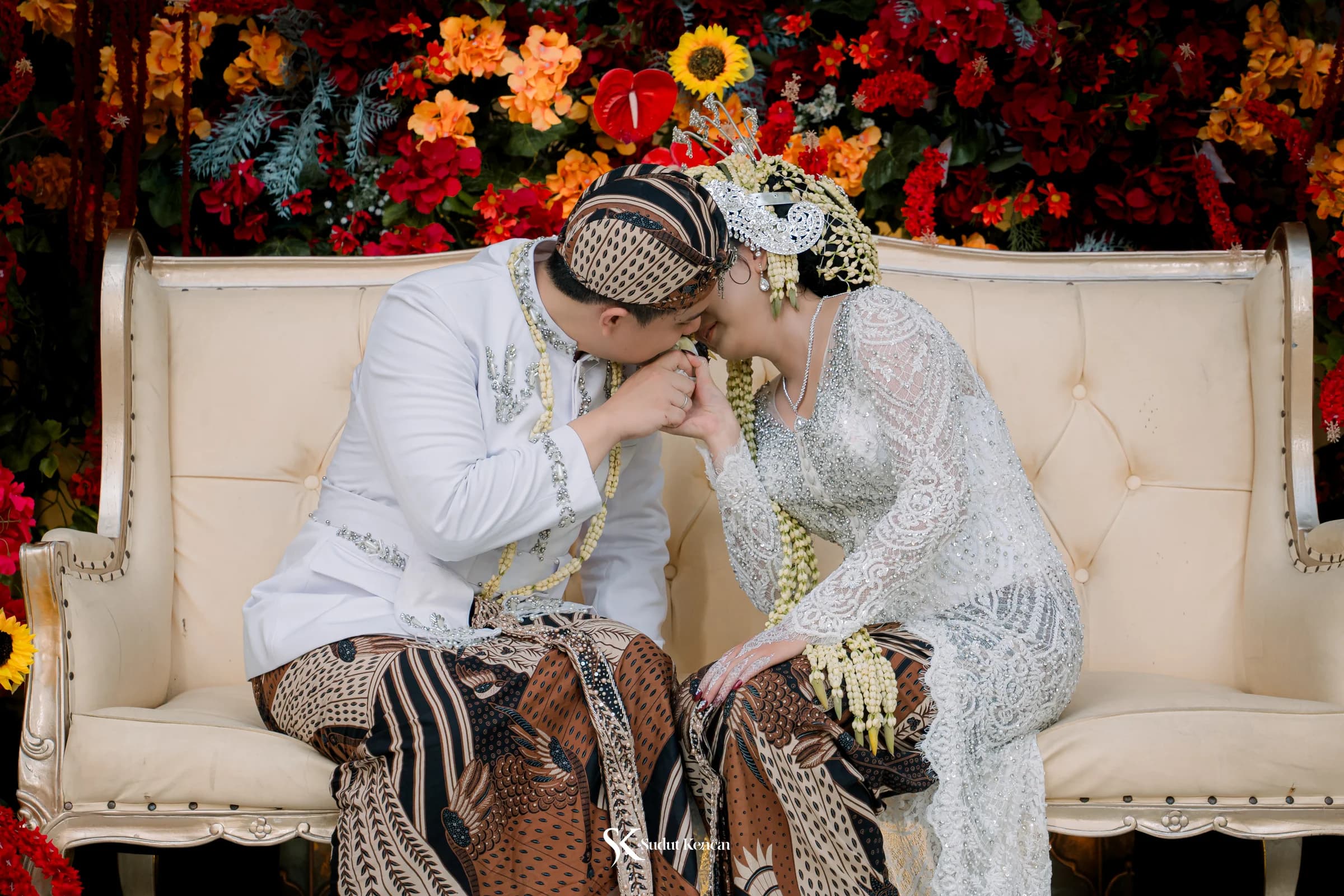 Momen romantis mempelai pria mencium tangan mempelai wanita di pelaminan